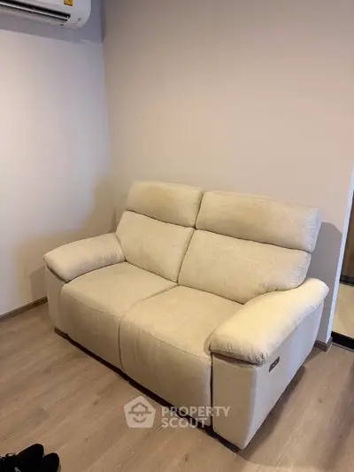 Cozy beige sofa in a modern living room with wooden flooring and neutral walls.
