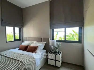 Cozy bedroom with modern decor and large windows offering natural light and garden views.