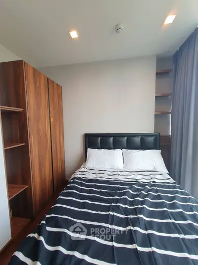 Modern bedroom with striped bedding and wooden wardrobe in a cozy apartment