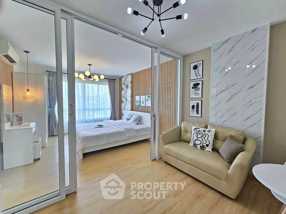 Modern bedroom with stylish decor and cozy seating area, featuring elegant lighting and large windows.