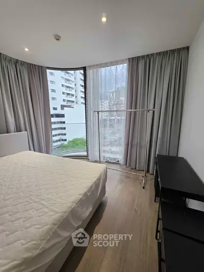 Modern bedroom with large window and city view in high-rise apartment