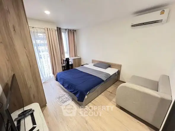 Modern bedroom with cozy bed, air conditioning, and natural light from large windows.