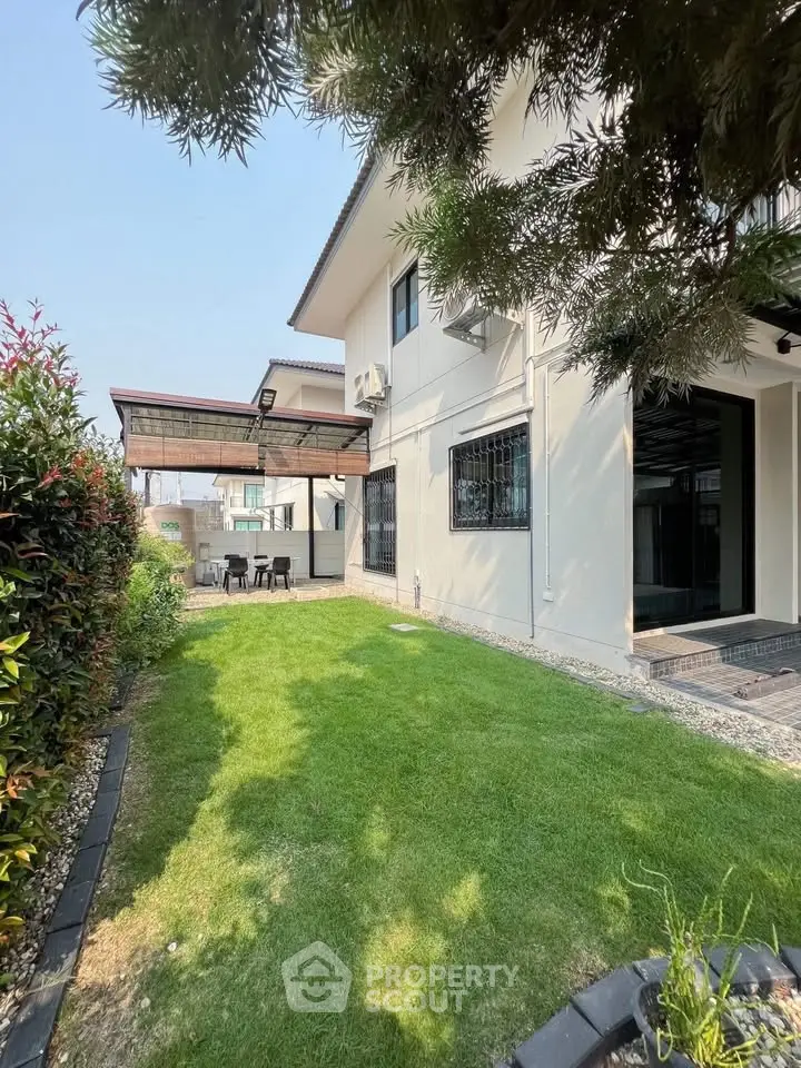 Stunning modern home with lush green garden and outdoor seating area.