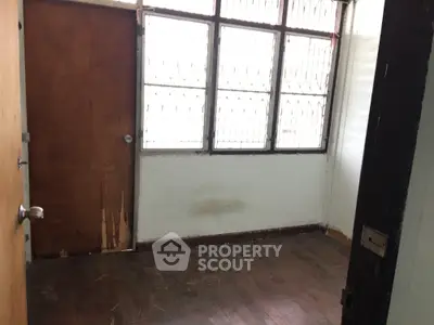 Cozy room with wooden floor and large windows, perfect for a small office or study space.