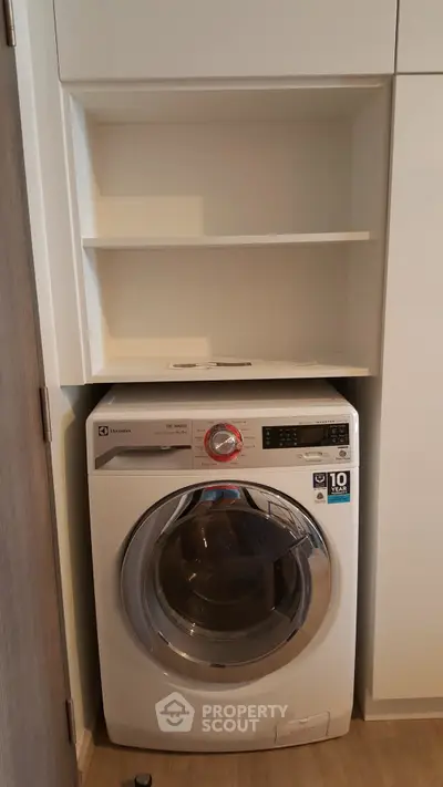 Modern laundry area with Electrolux washing machine in compact storage space.
