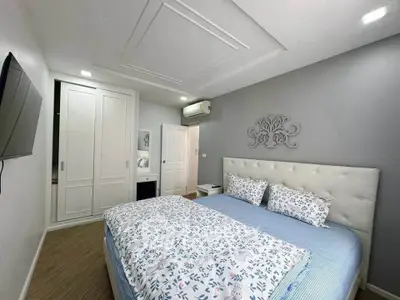 Modern bedroom with stylish decor and built-in wardrobe, featuring a cozy bed and wall-mounted TV.