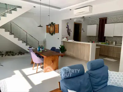 Modern open-plan living room with stylish kitchen and dining area, featuring sleek furniture and natural light.