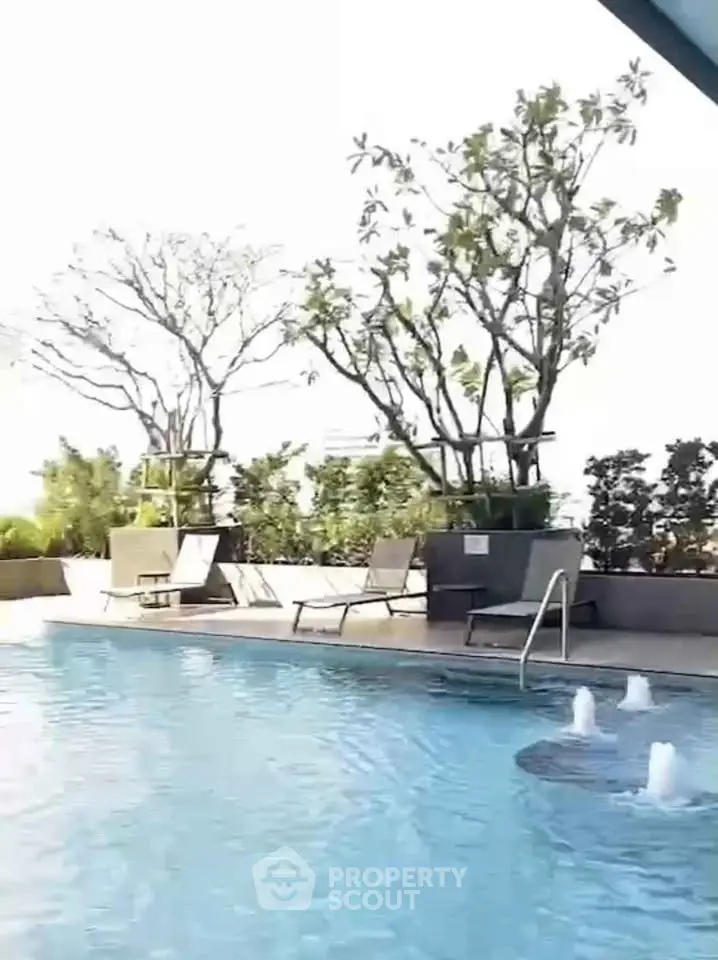 Luxurious rooftop pool with sun loungers and lush greenery, perfect for relaxation.