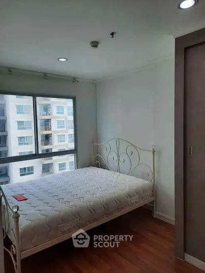 Bright bedroom with large window and elegant metal bed frame in modern apartment.