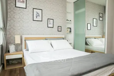 Modern bedroom with elegant decor, featuring a cozy bed, stylish wallpaper, and framed art, perfect for relaxation.