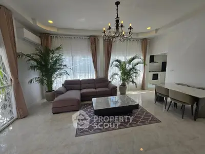 Elegant living room with chandelier, modern sofa, and lush plants