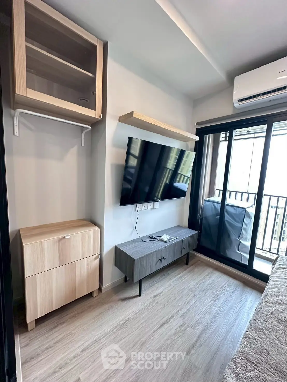Modern living room with sleek TV setup and balcony access in a stylish apartment.