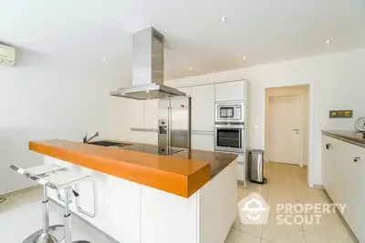 Spacious modern kitchen with stainless steel appliances, ample cabinetry, and a sleek island counter in a bright, airy space.