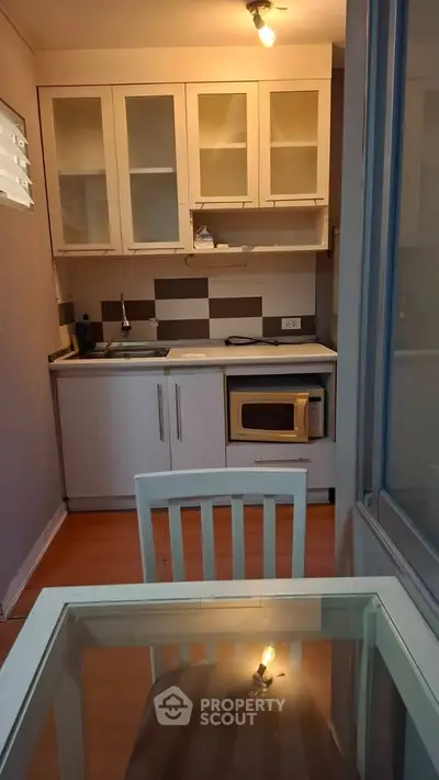 Cozy compact kitchen with modern appliances and dining area in a stylish apartment.