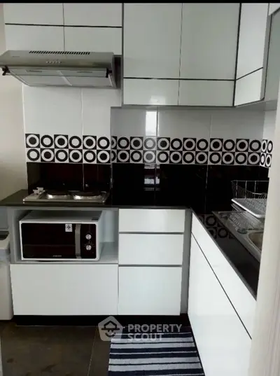 Modern kitchen with sleek cabinetry and stylish backsplash in a compact layout.