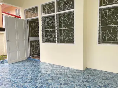 Charming patio with decorative tile flooring and secure window grills, perfect for relaxation.