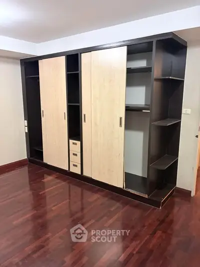 Spacious bedroom with elegant wooden wardrobe and polished hardwood floors.