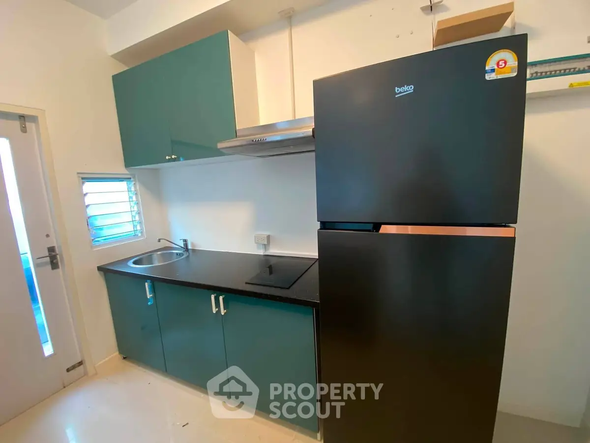 Modern compact kitchen with sleek cabinetry and energy-efficient refrigerator