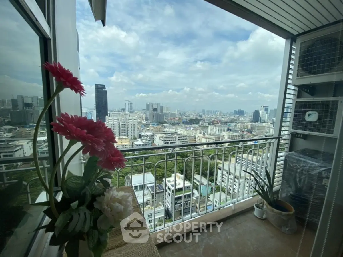 Stunning cityscape view from a high-rise balcony with vibrant flowers and clear skies.