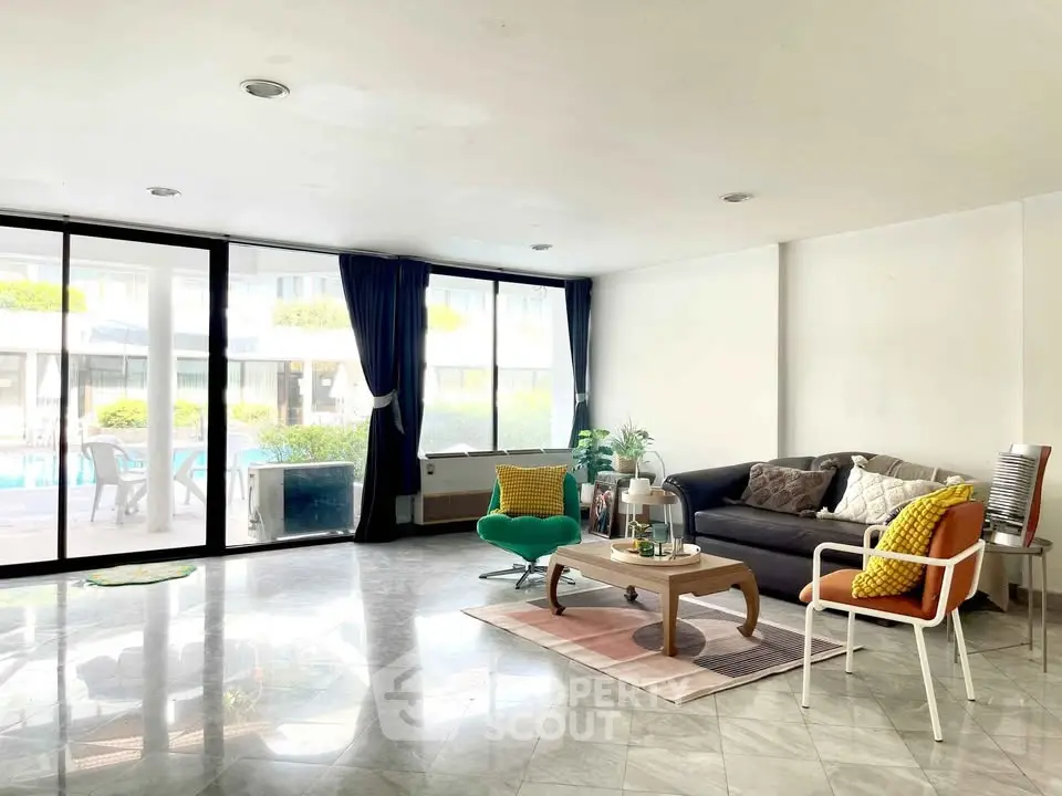 Spacious living room with modern decor and pool view, perfect for relaxation and entertaining.