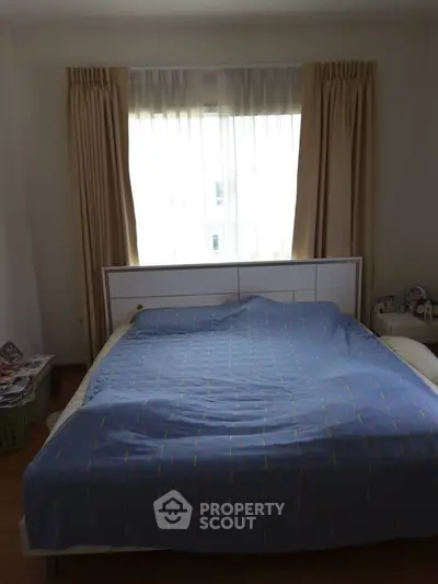 Cozy bedroom with natural light and modern furnishings, perfect for relaxation.
