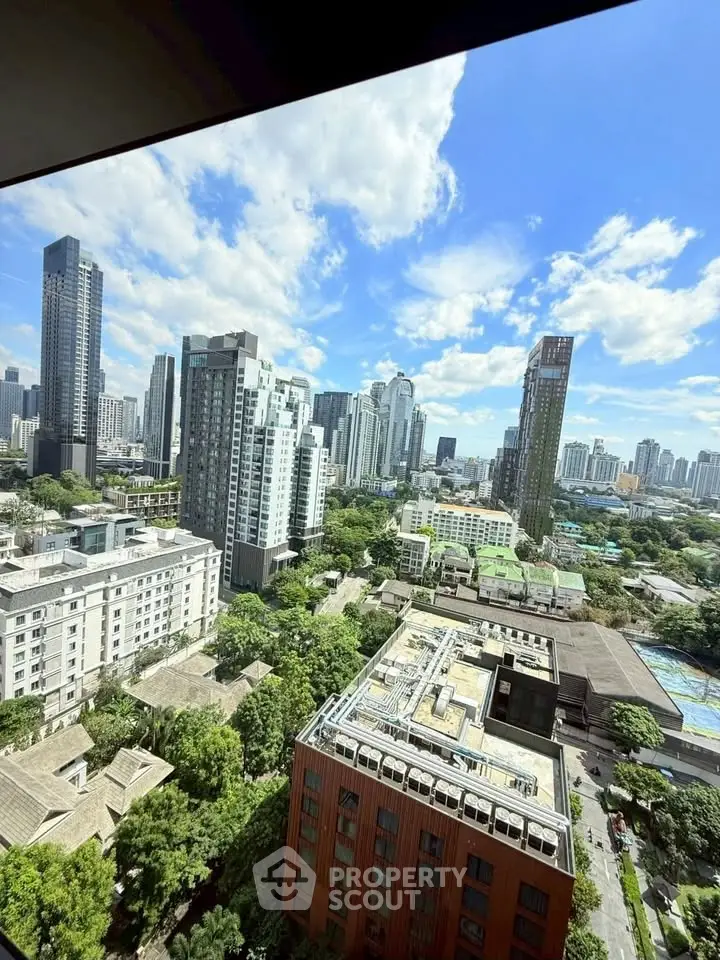Stunning cityscape view from high-rise apartment showcasing urban skyline and lush greenery.