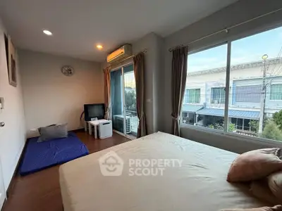 Spacious bedroom with large window and modern decor in a cozy apartment.