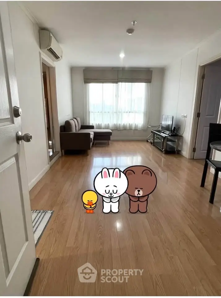 Spacious living room with wooden flooring and modern furnishings in a bright apartment.