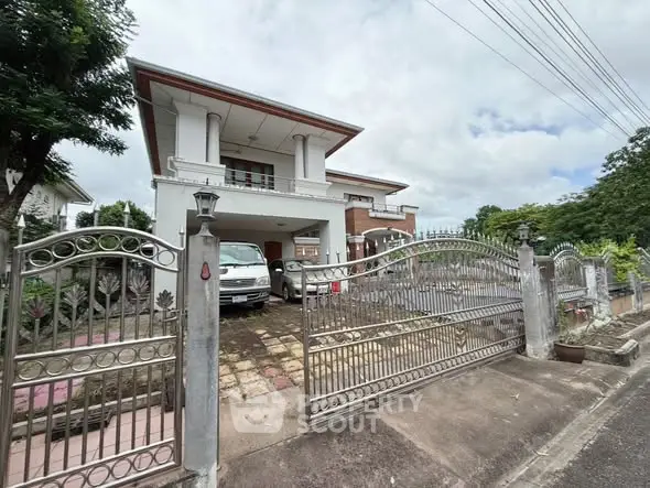 Elegant two-story house with gated driveway and lush greenery