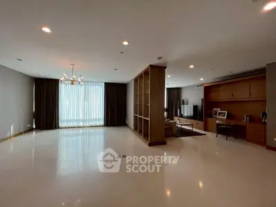 Spacious living room with elegant chandelier and large windows in modern apartment.