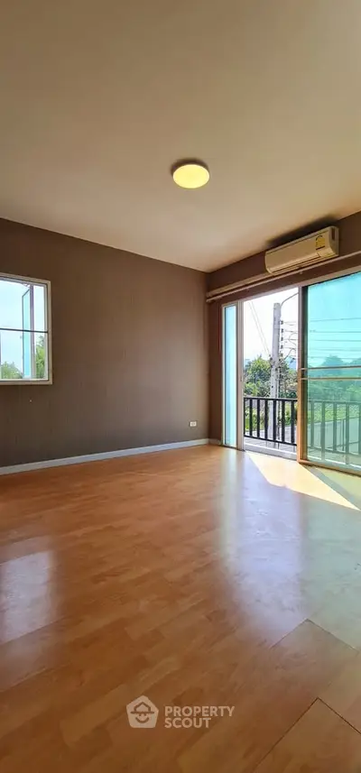 Spacious room with wooden flooring and balcony access, ideal for modern living.
