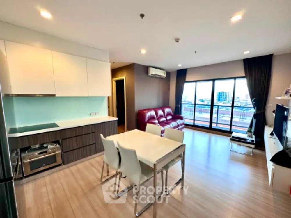 Modern open-layout living room with kitchen, featuring city view and stylish furnishings.