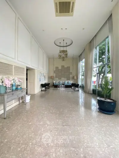 Elegant lobby with high ceilings, large windows, and stylish decor in a luxurious building.