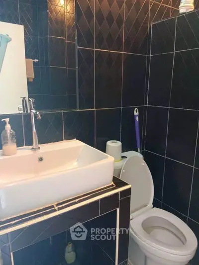 Modern bathroom with sleek black tiles and contemporary fixtures.