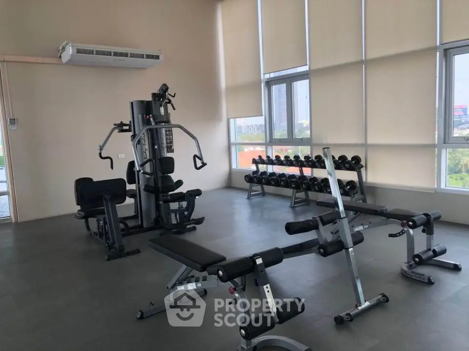 Spacious modern gym with state-of-the-art equipment and large windows offering city views.