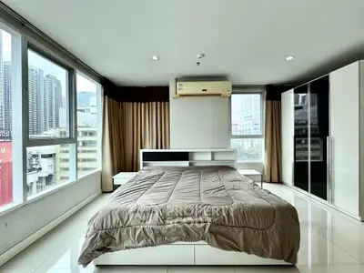 Spacious bedroom with city view and modern furnishings in high-rise apartment.