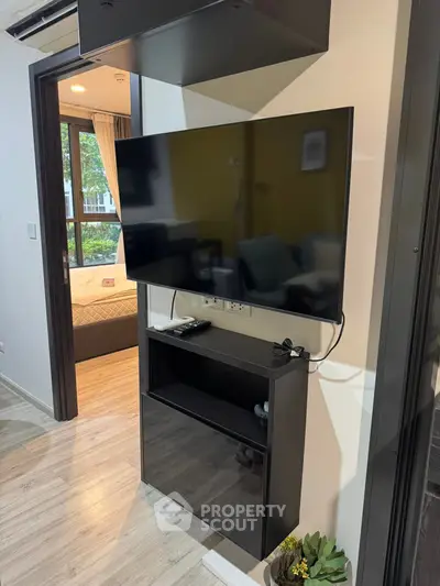 Modern apartment interior with wall-mounted TV and view into cozy bedroom