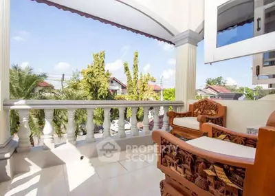 Charming balcony with ornate wooden furniture and scenic view in a serene neighborhood.