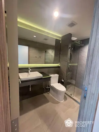 Modern bathroom with sleek design, glass shower, and ambient lighting.