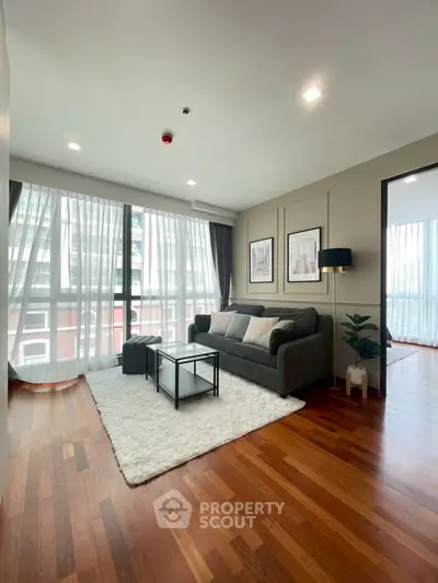 Spacious living room with modern decor and large windows in a stylish apartment.