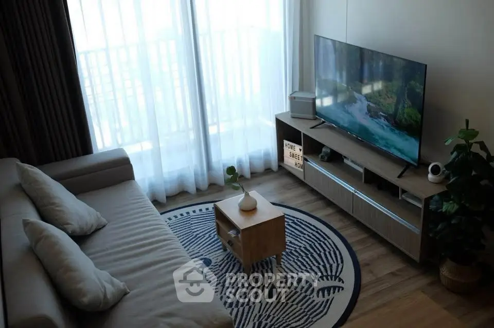 Modern living room with cozy sofa and large TV, featuring natural light and stylish decor.