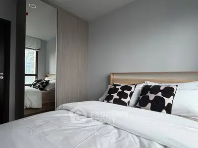Modern bedroom with stylish decor and large window offering natural light.