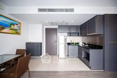 Modern kitchen with sleek cabinets and dining area in open layout apartment.