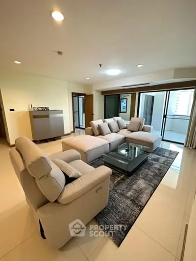 Spacious living room with modern furniture and large windows in a high-rise apartment.