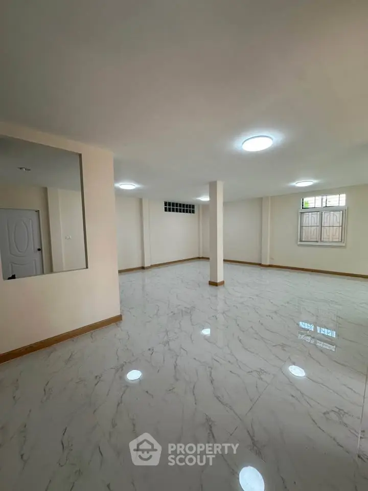 Spacious modern living room with marble flooring and ample natural light.