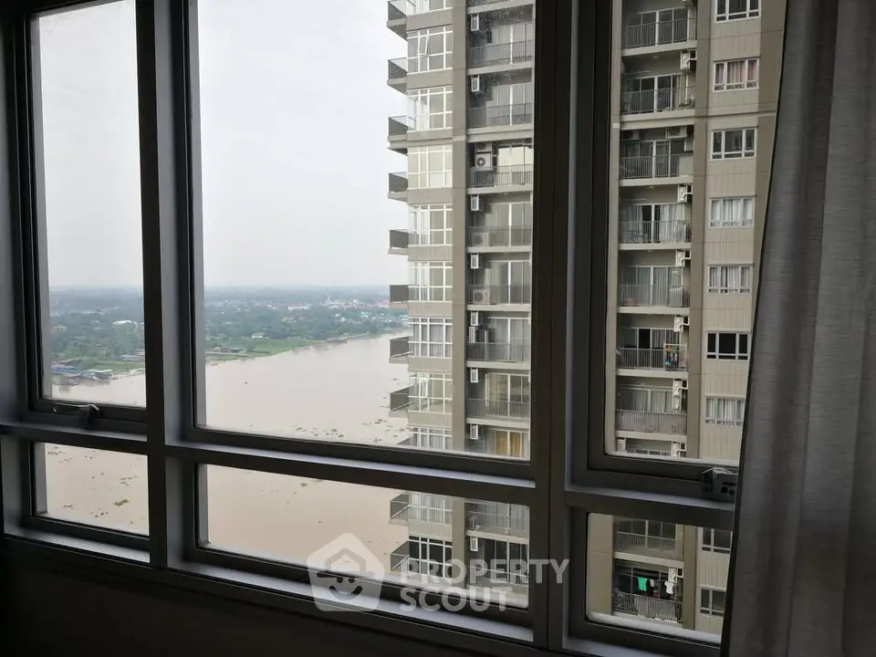 Stunning river view from high-rise apartment window, showcasing serene water and neighboring building.