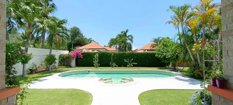 Stunning backyard with lush garden and inviting swimming pool under clear blue sky.