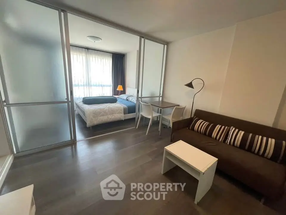 Modern studio apartment with cozy living area and bedroom separated by glass partition.