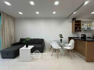 Modern open-plan living room with sleek furniture and stylish kitchen area.