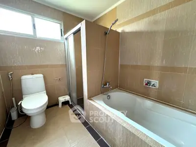 Spacious bathroom with modern bathtub and shower in elegant beige tiles.
